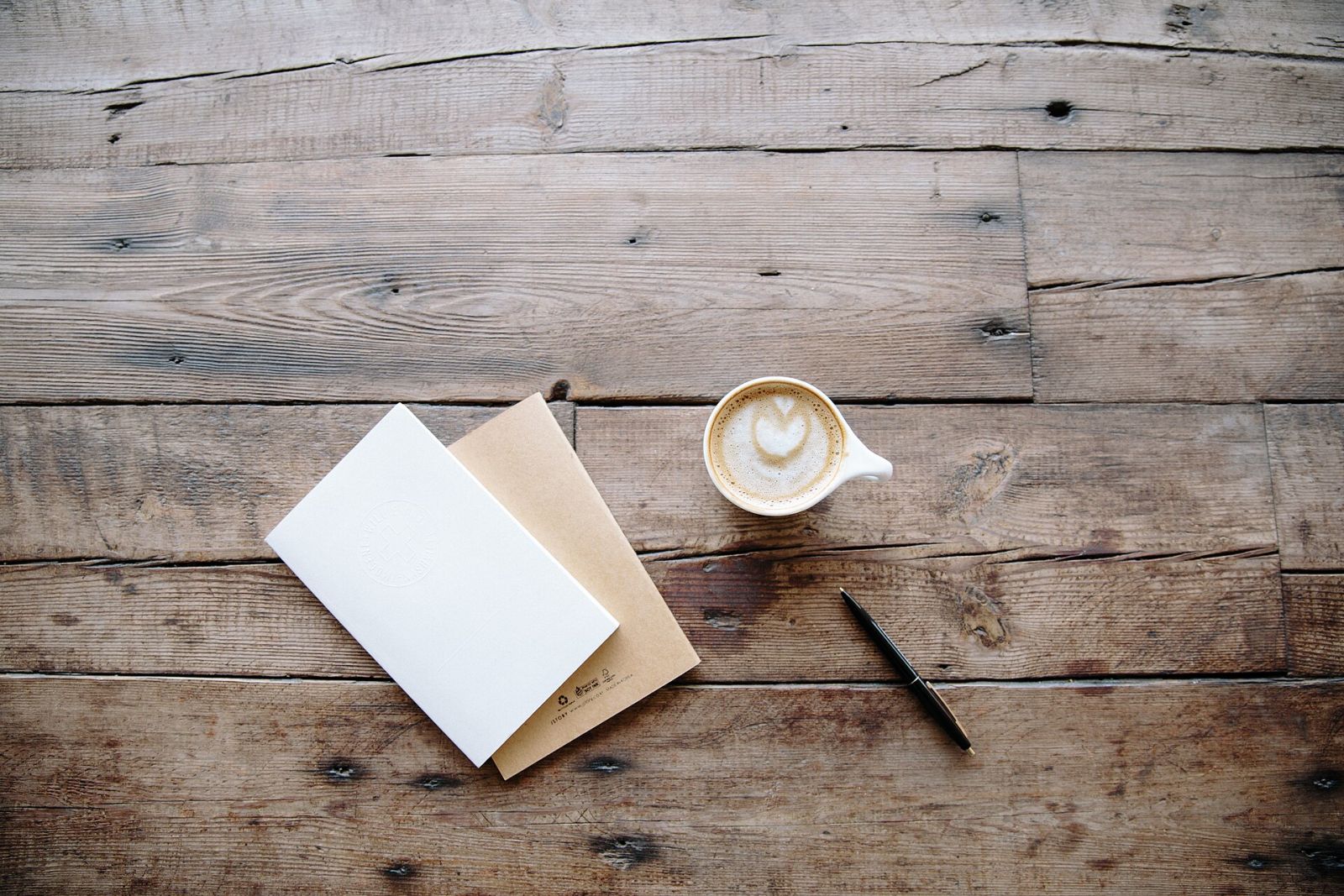 Carnet, enveloppe et café posés sur une table en bois